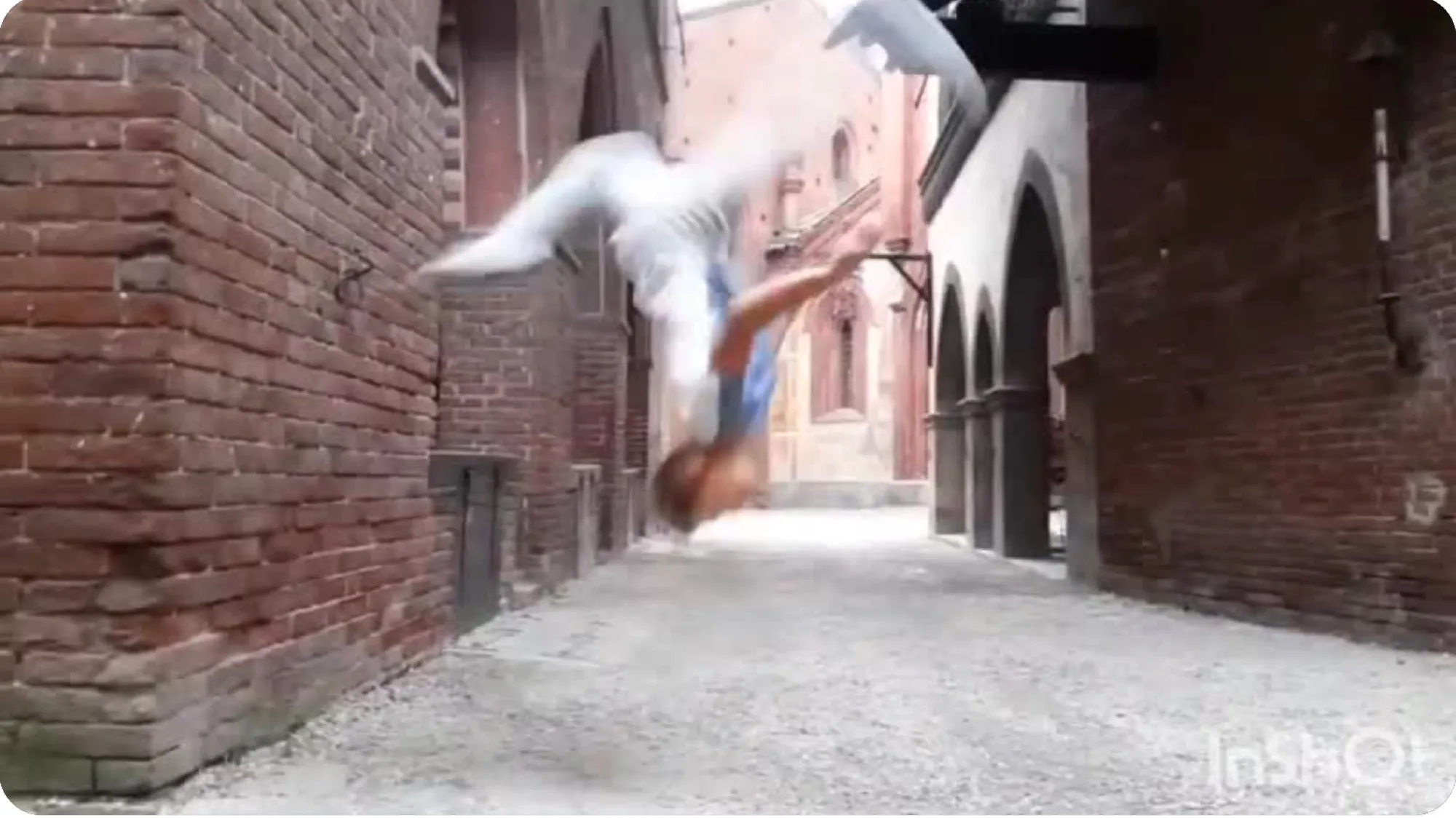 Acrobat mid-flip in a brick alley